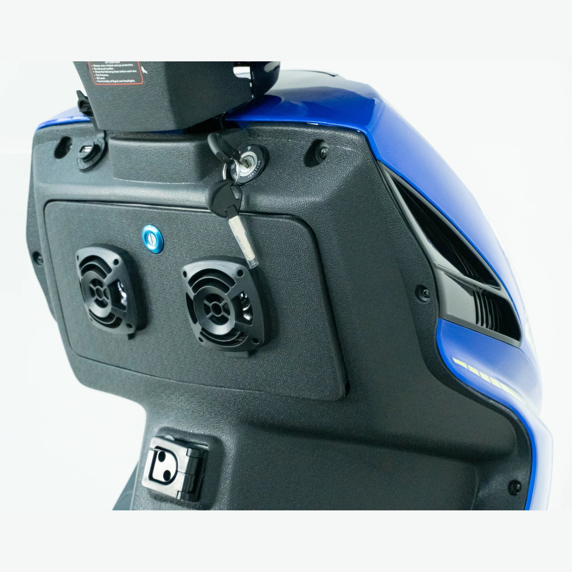 Close-up of blue scooter dashboard with ignition key and built-in speakers
