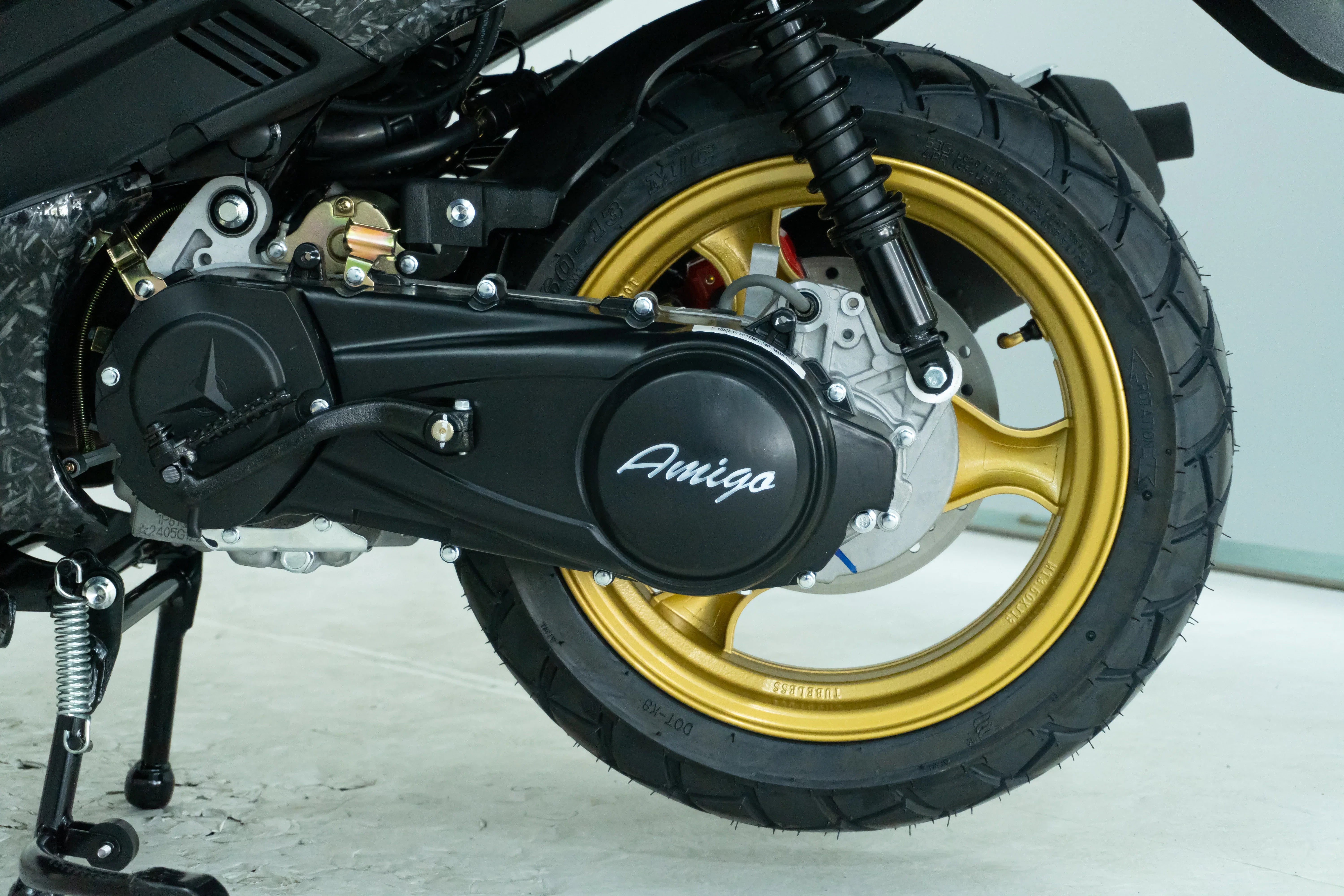 Amigo scooter rear wheel with gold rim and black tire, showcasing engine and suspension details