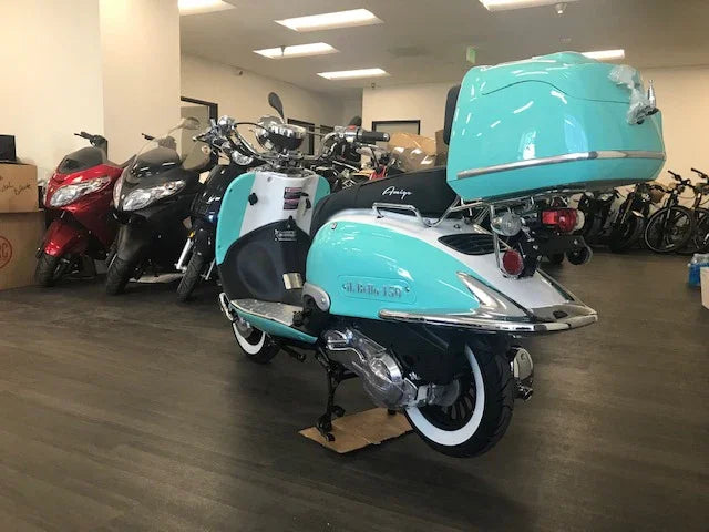 Aqua and white retro style scooter with top box in a showroom with other scooters and bikes