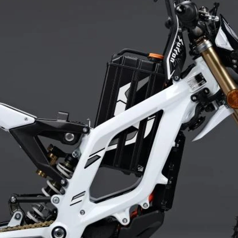 Close-up of white Surron frame with integrated battery pack and suspension details