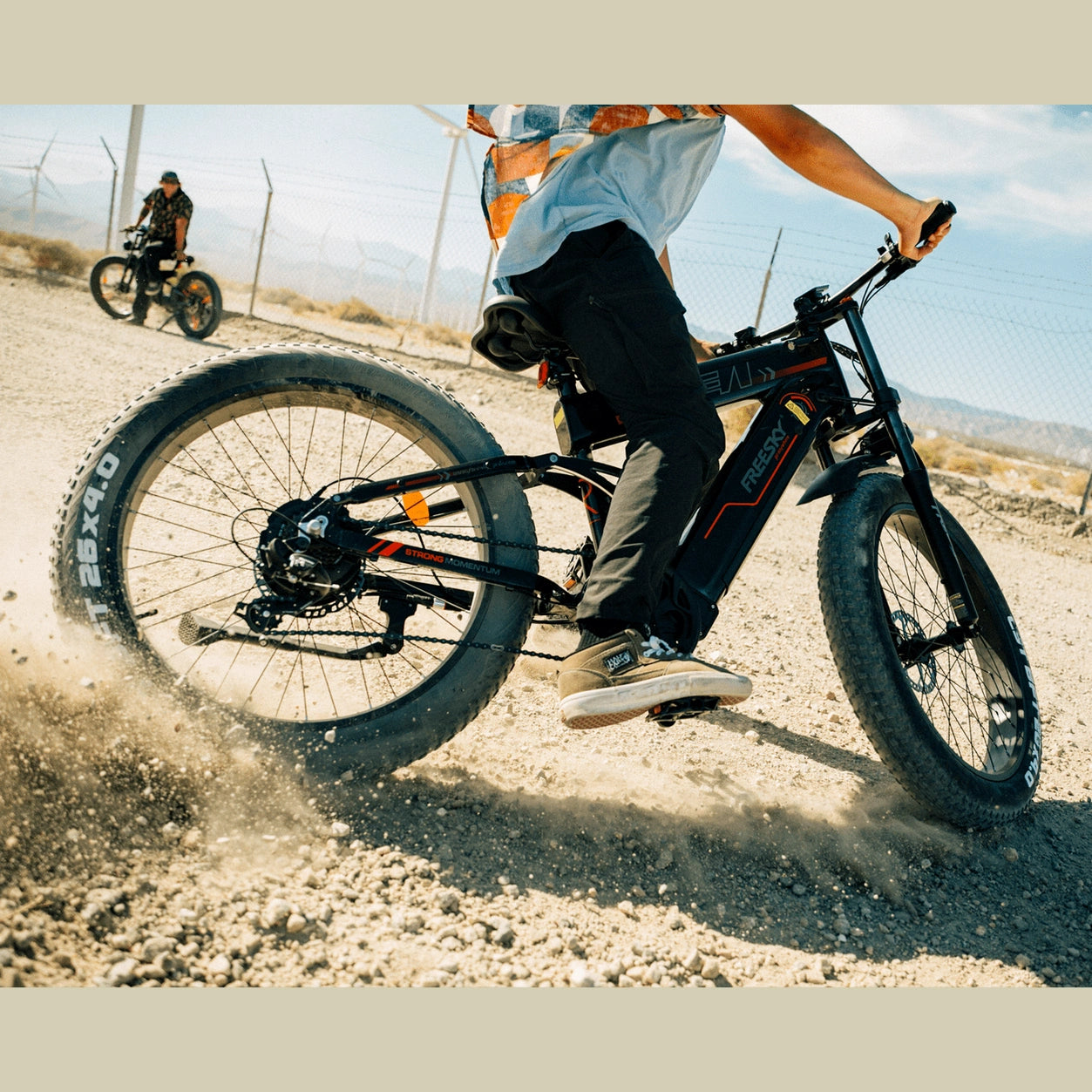 Rider on black Freesky electric fat tire bike kicking up dust on a gravel dirt trail