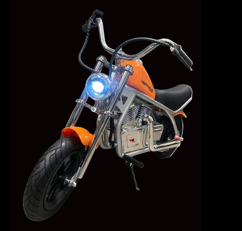 An orange and silver electric motorcycle designed for kids, featuring a small front wheel and a larger rear wheel, with LED lights on the front.