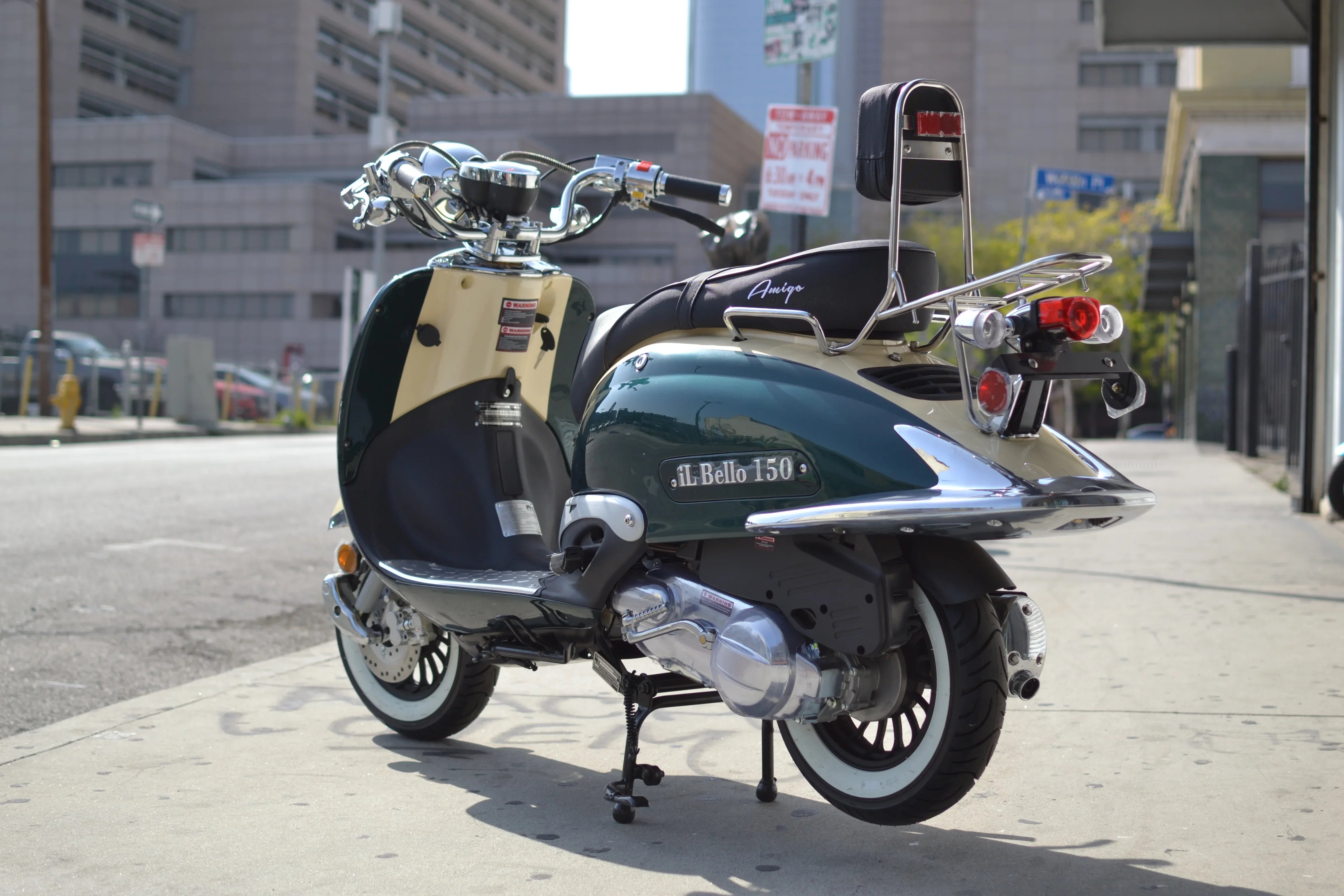 Green and cream Amigo Il Bello 150cc scooter parked on city sidewalk, rear view