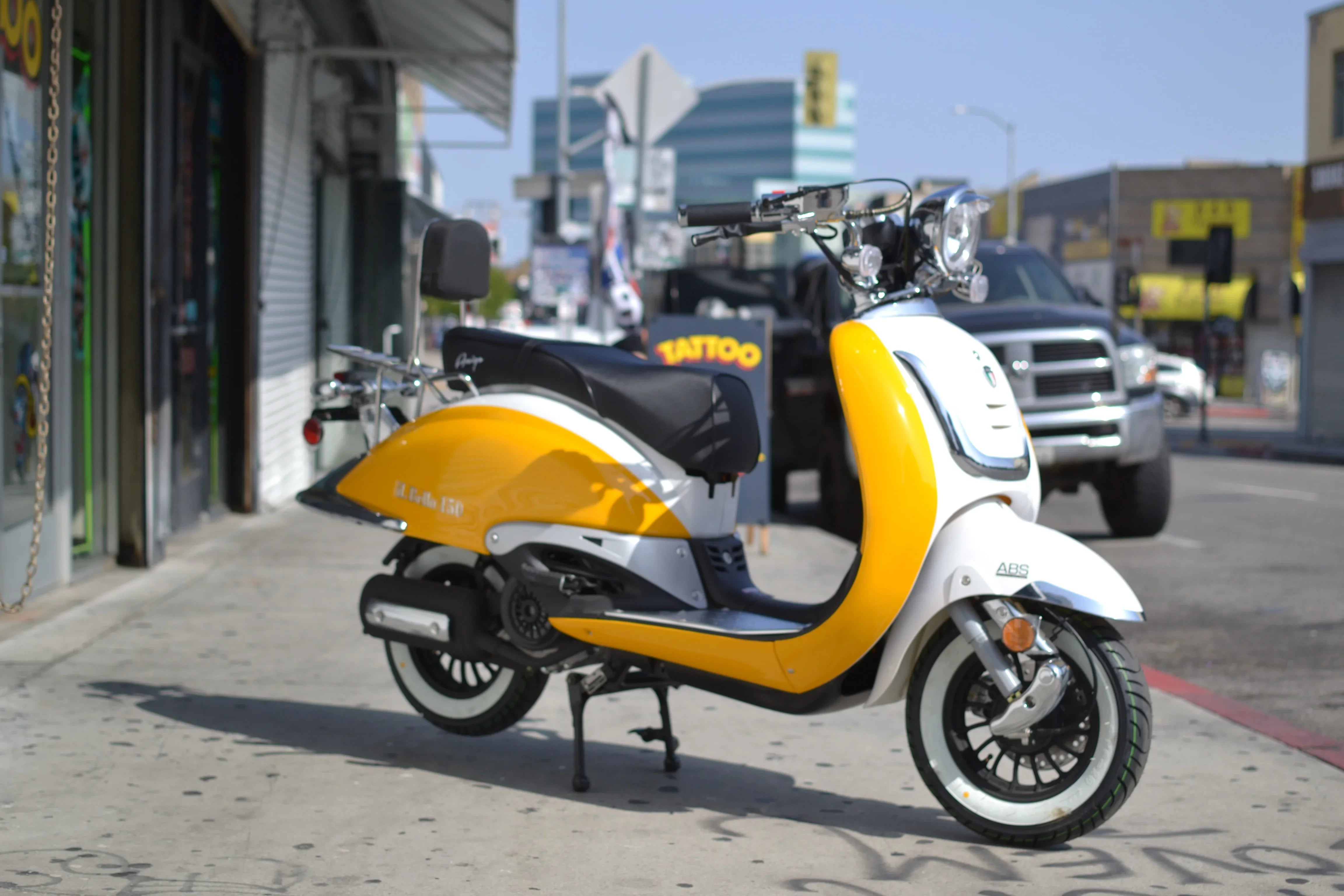 Yellow and white El Gallo 150cc scooter parked on a city sidewalk