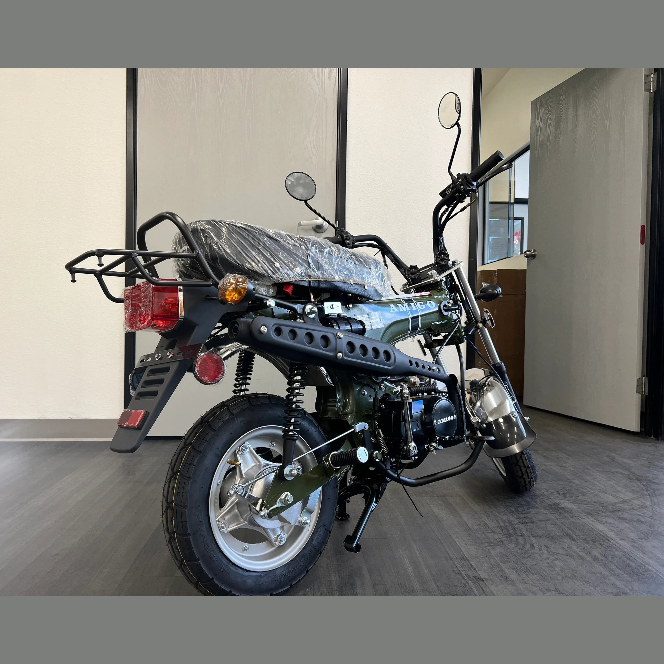 Green Amigo Rocky 125cc mini motorcycle rear view with exposed engine and luggage rack