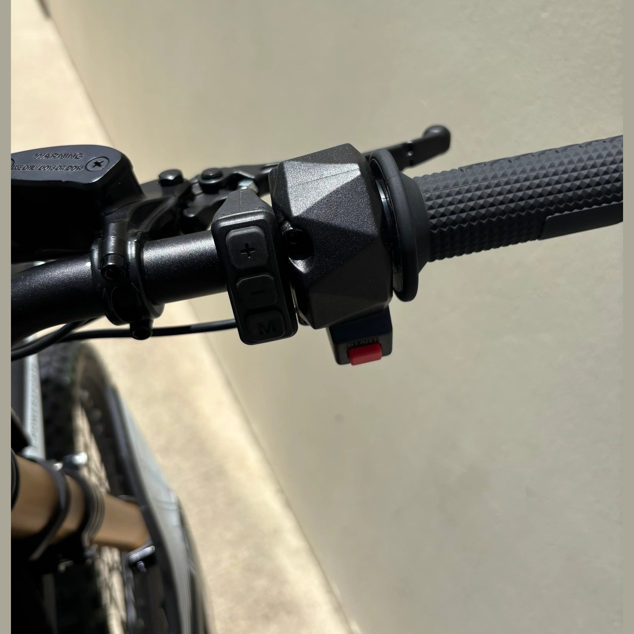 right handlebar controls of black Atlis Sigma electric dirt bike with start button