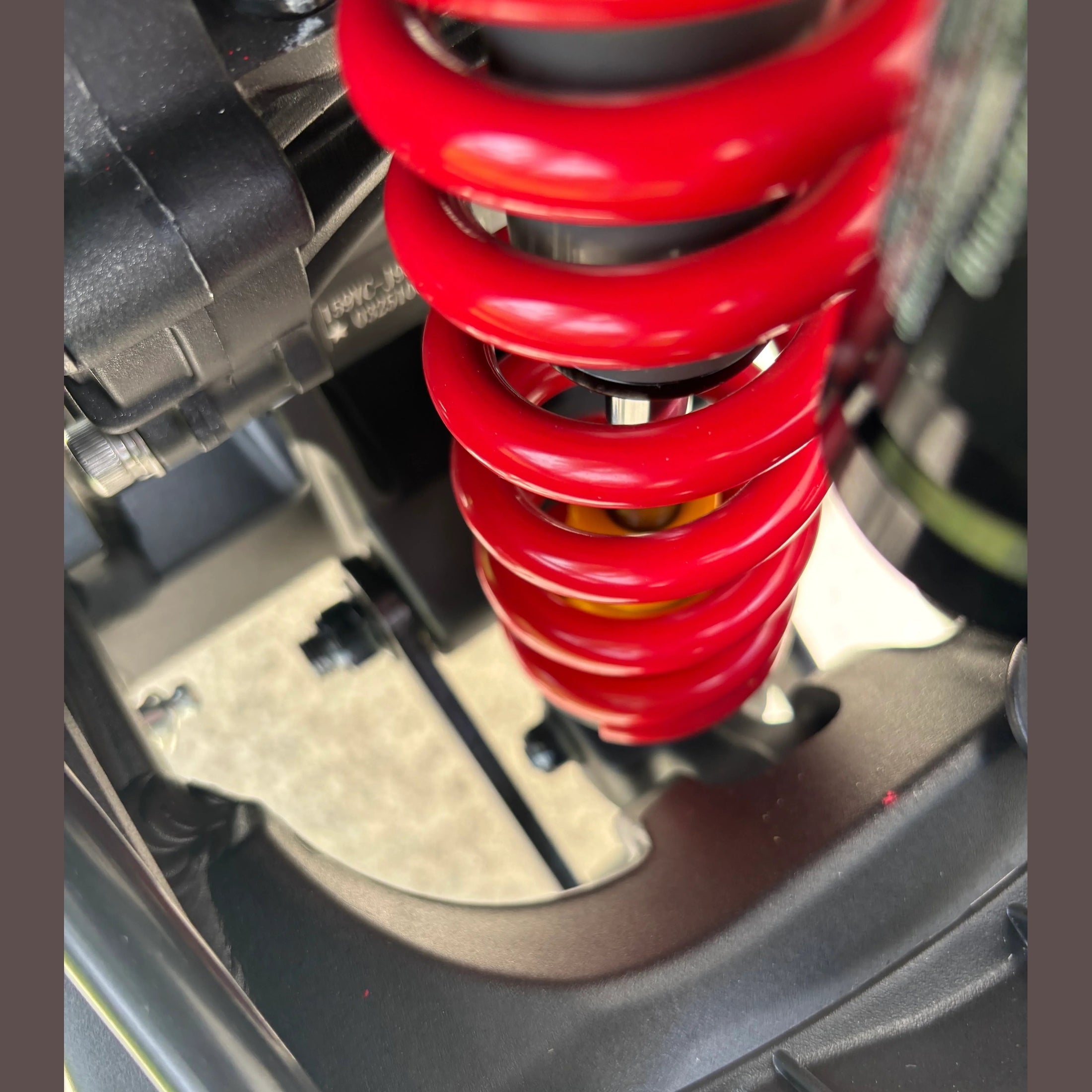 red coil rear shock absorber detail on black Atlis Sigma electric dirt bike frame