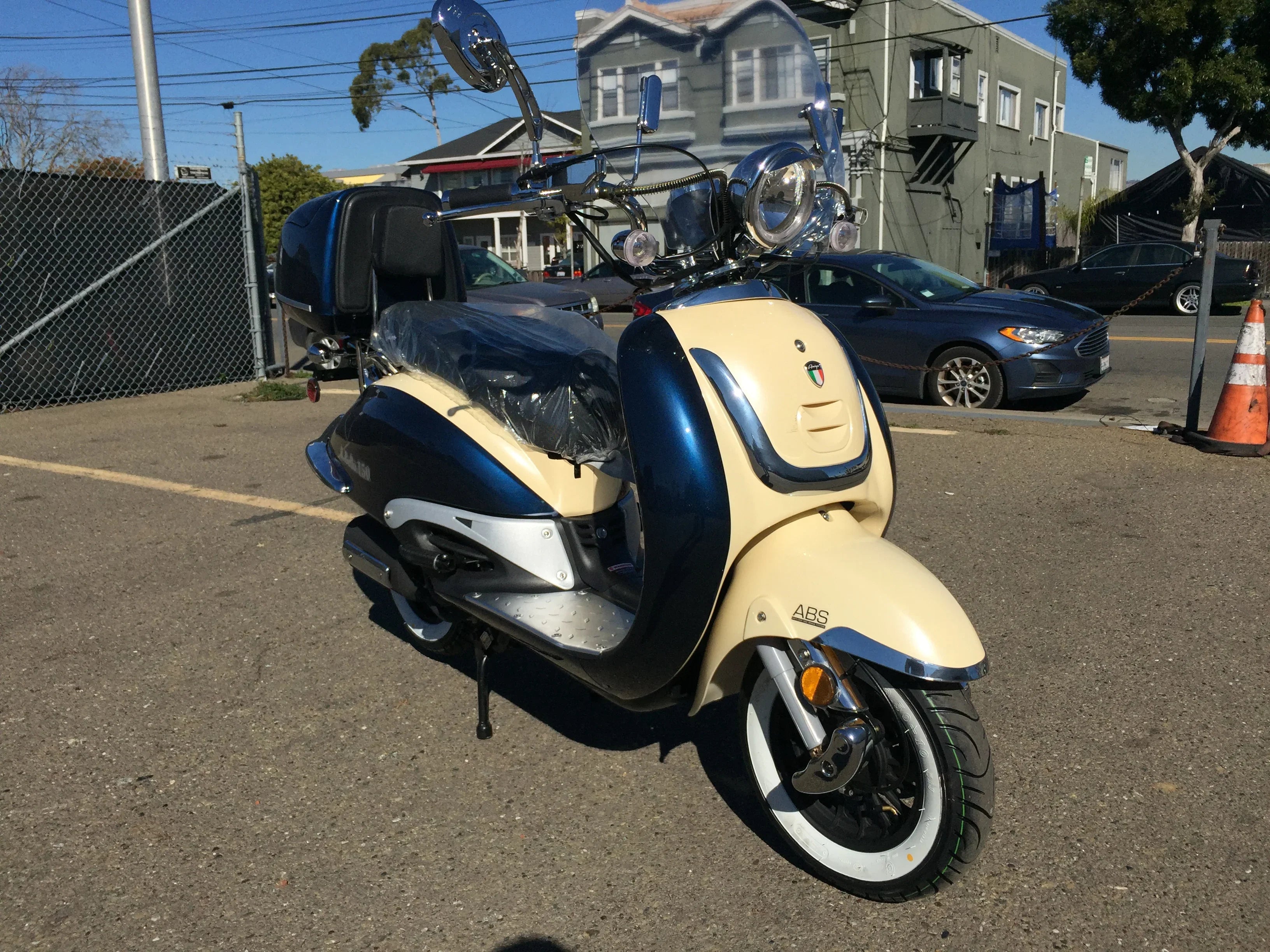 Blue and cream retro style scooter with windshield and rear storage, parked outdoors