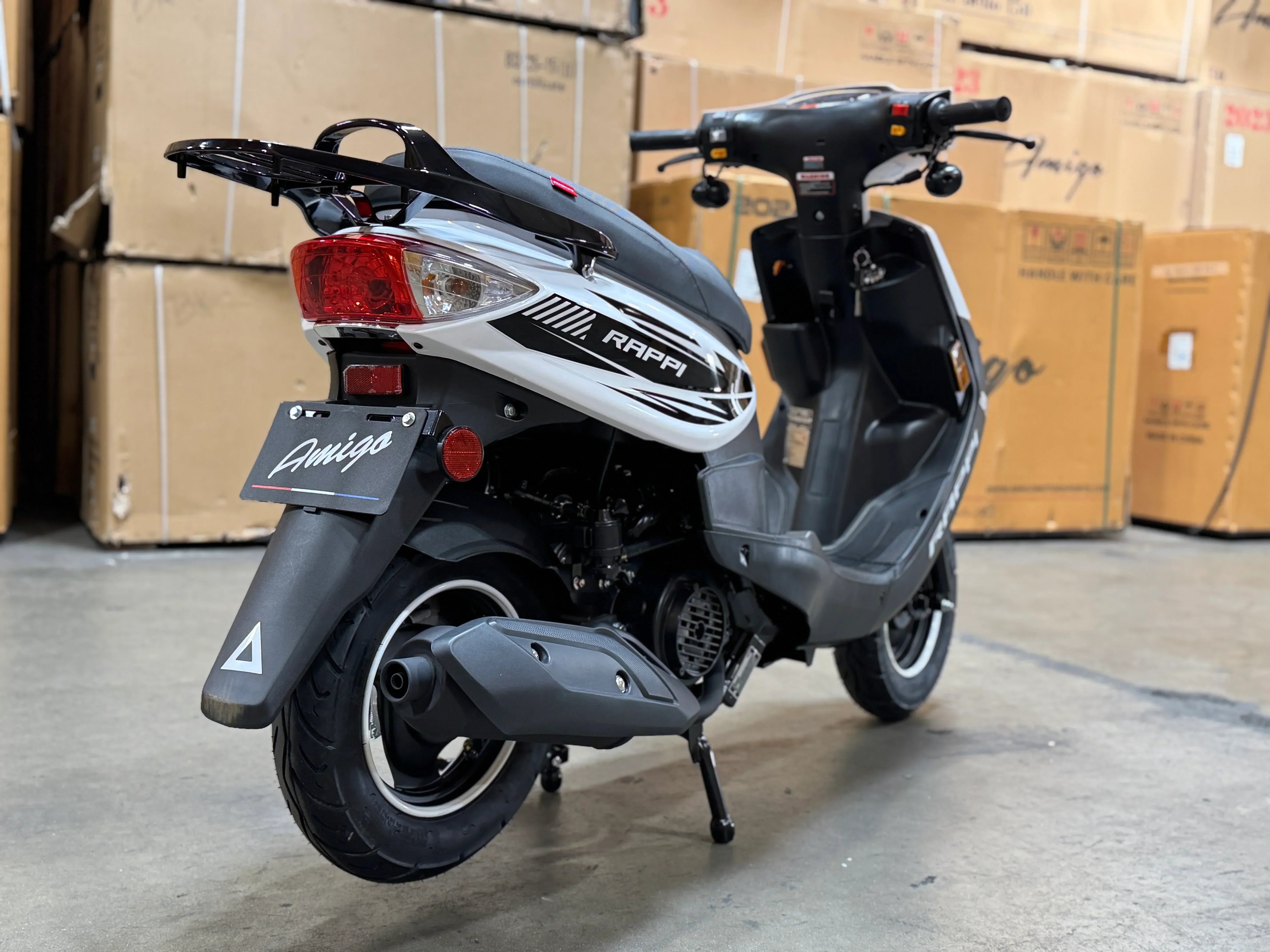 Rappi Amigo scooter in warehouse, sleek black and white design with rear rack and taillight