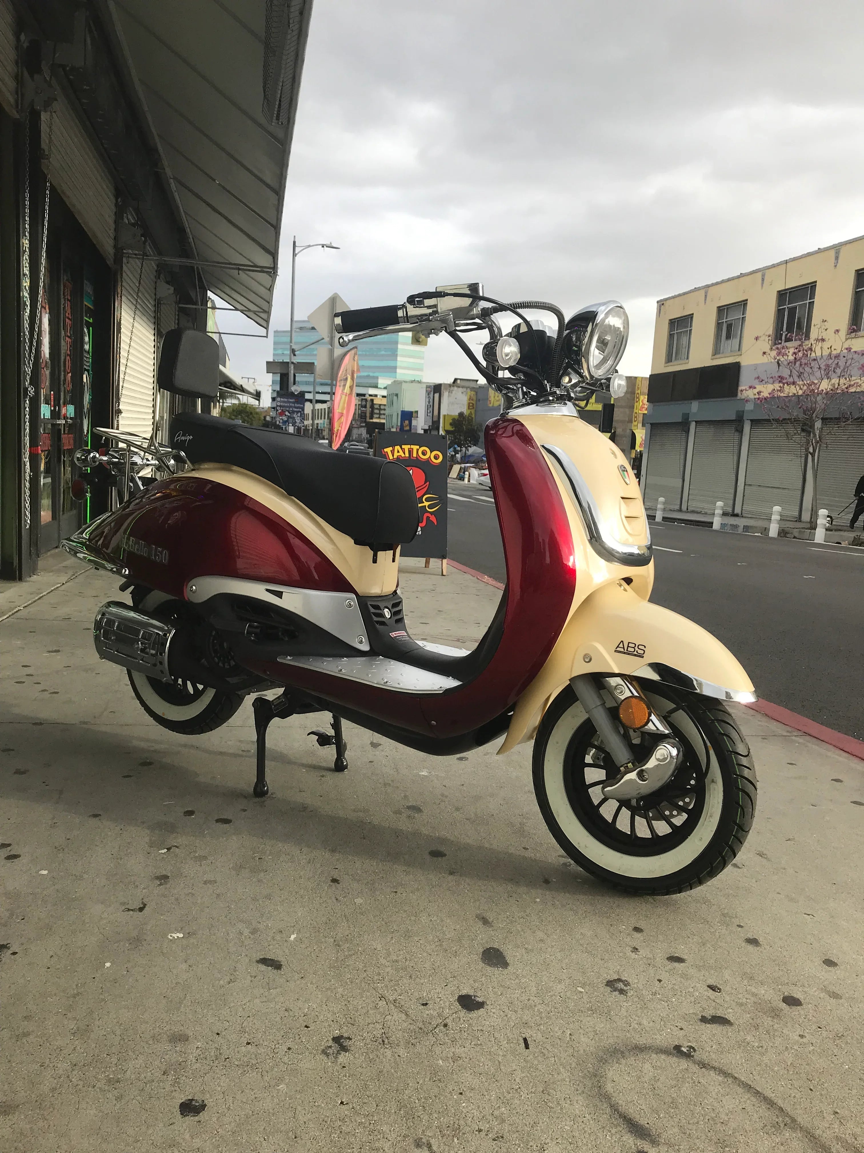 Retro style red and cream scooter with ABS brakes parked on urban sidewalk