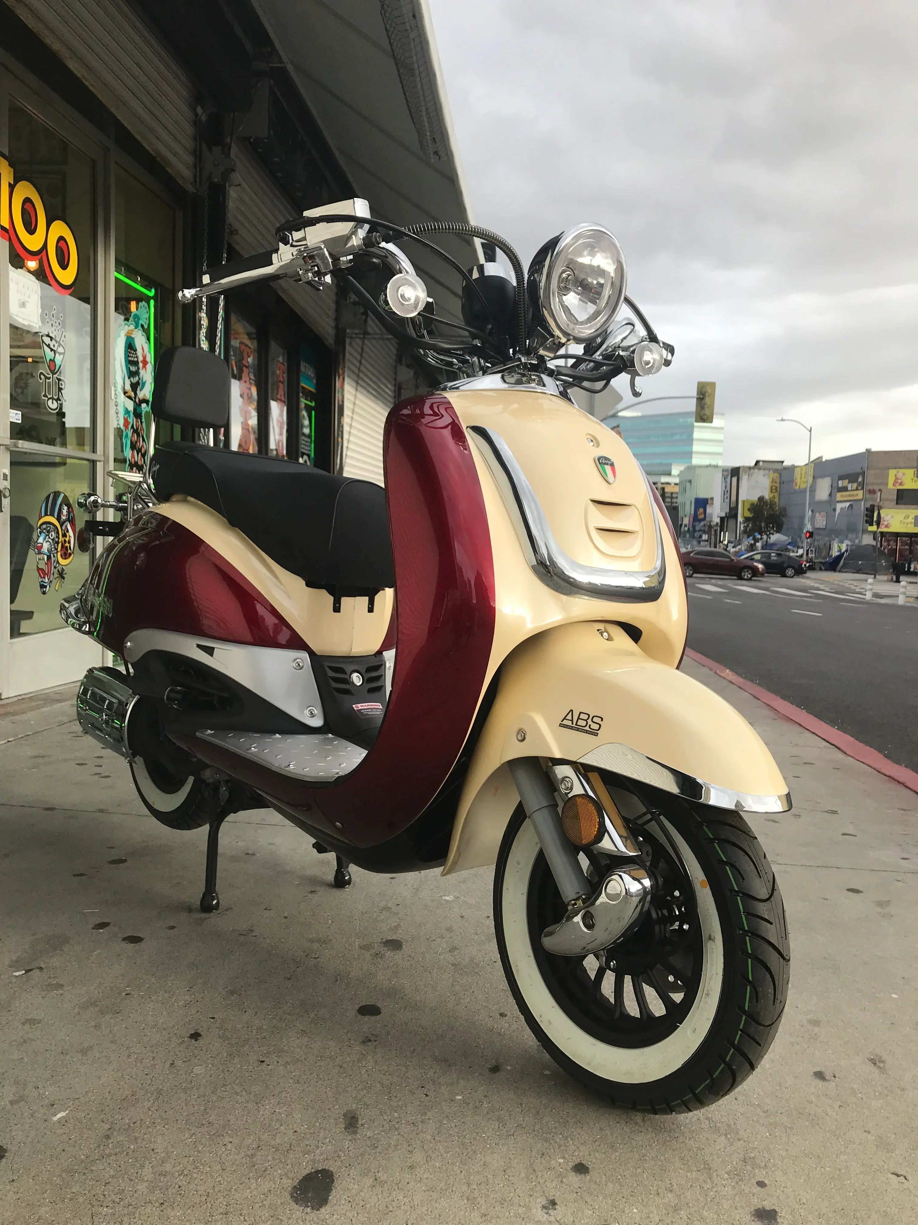 Retro-style cream and red motor scooter with ABS parked on a city street