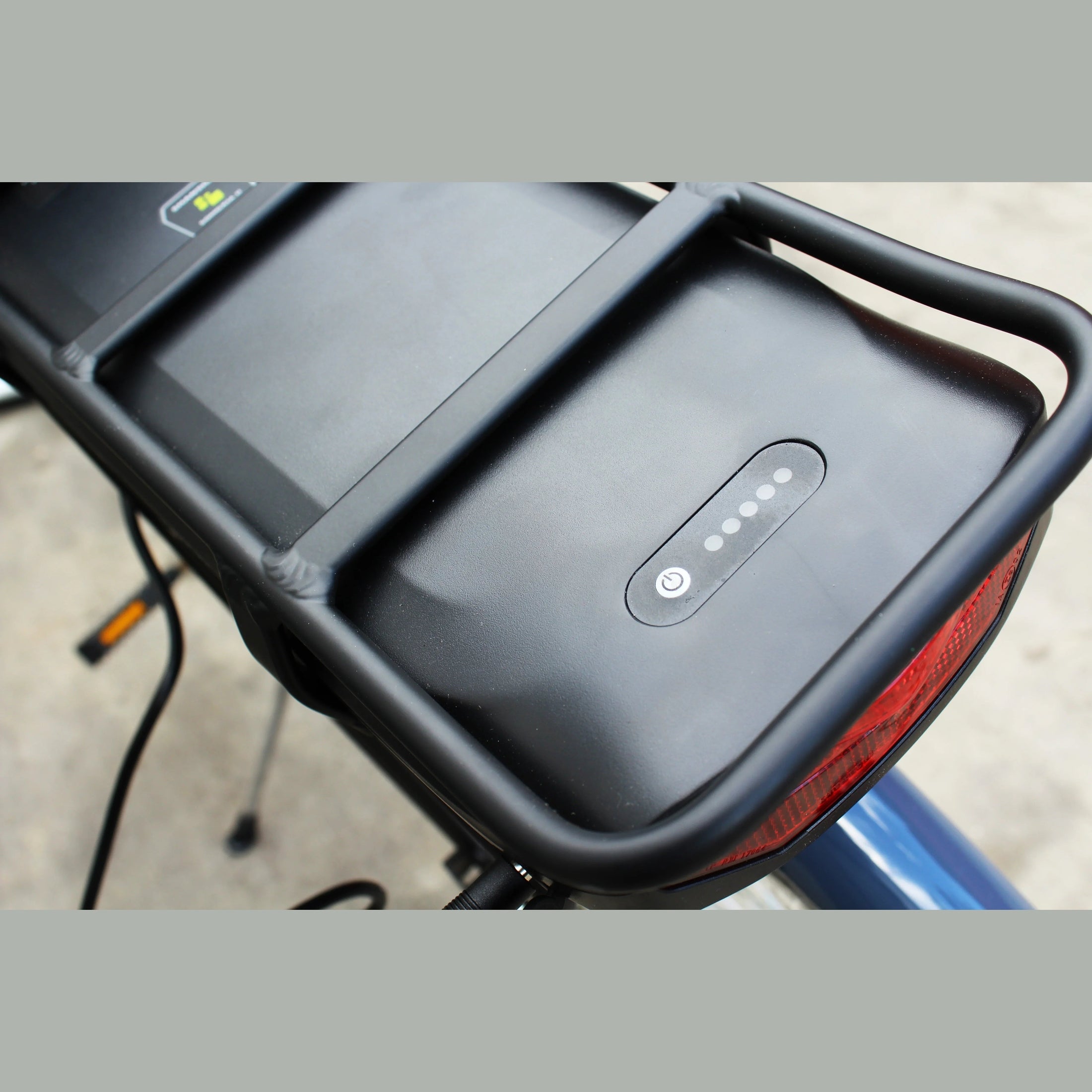 Close-up of black rear battery pack with LED indicators on electric bike