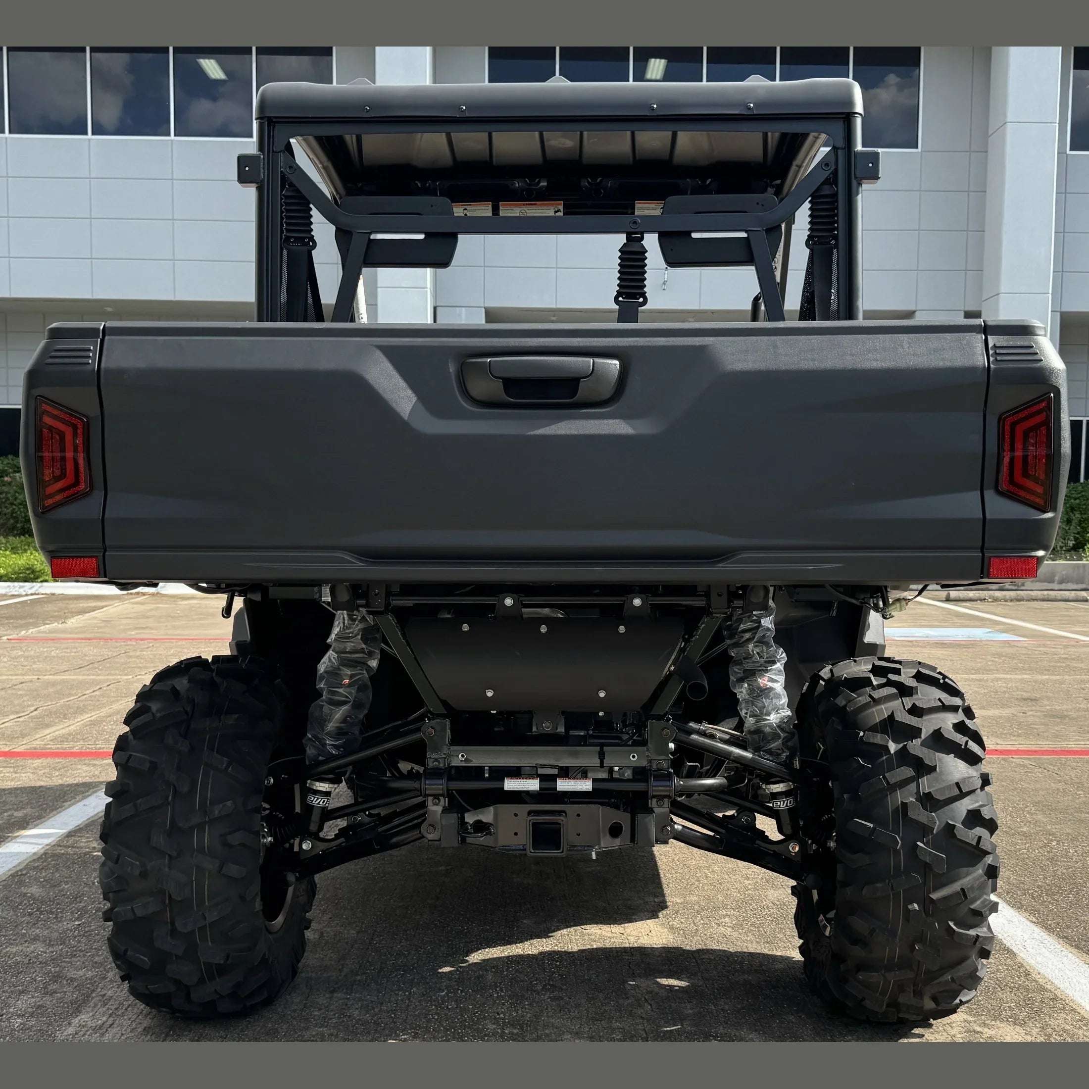 Rear view of gray utility task vehicle with large off-road tires and cargo bed, parked outdoors.