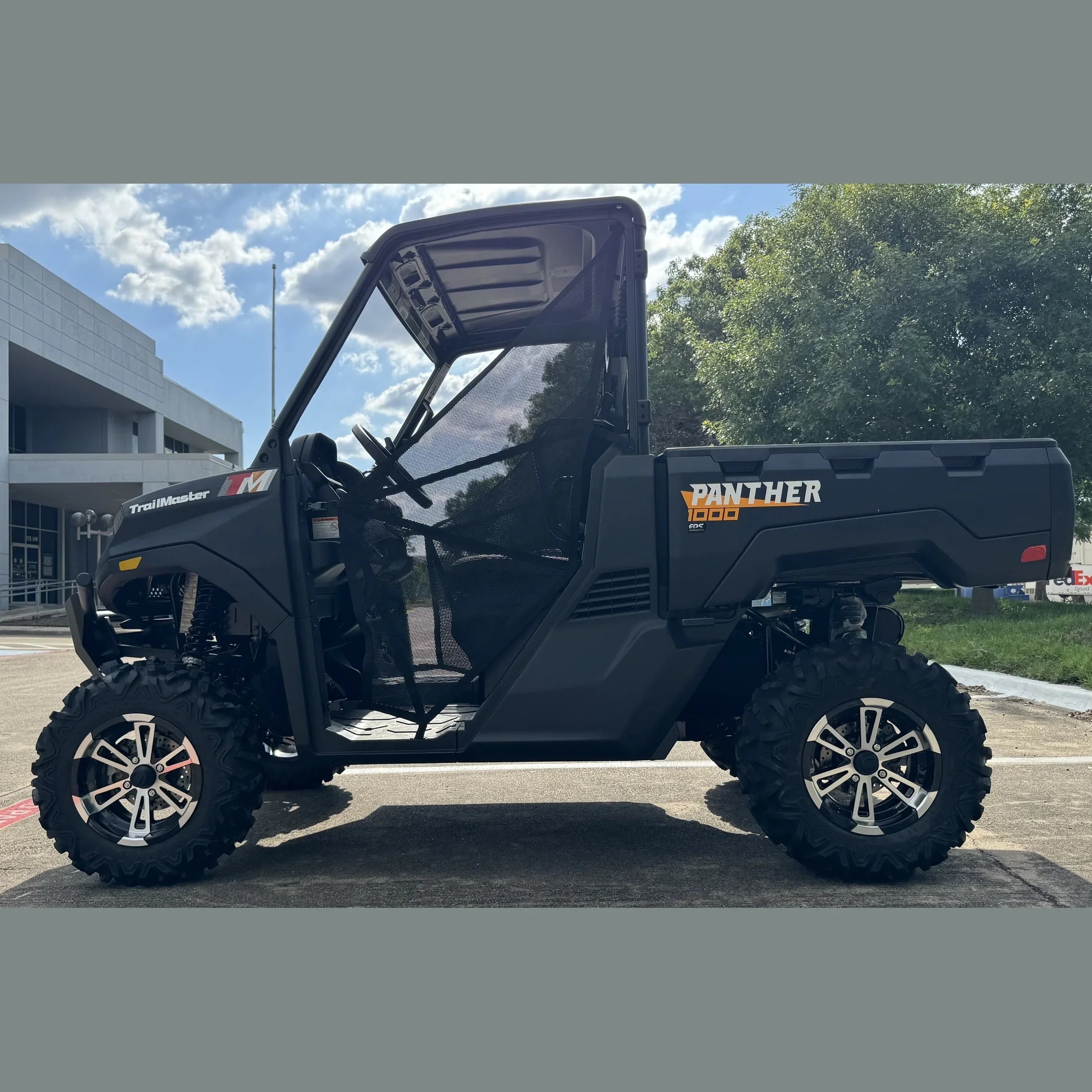 TrailMaster Panther 1000 UTV with mesh doors, rugged tires, and open cab parked outdoors