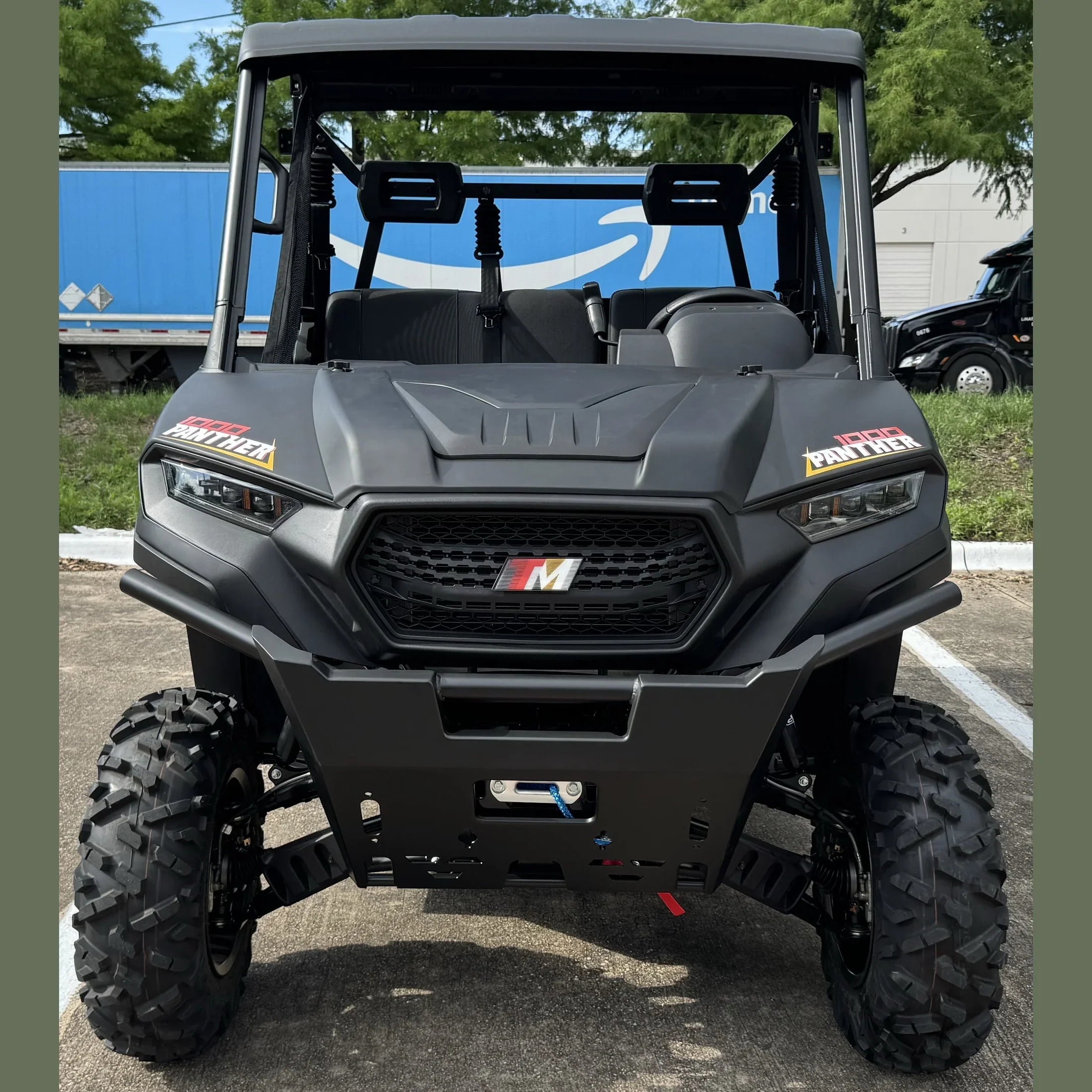 Black 1000 Panther UTV with rugged tires and front winch, parked outdoors near delivery truck