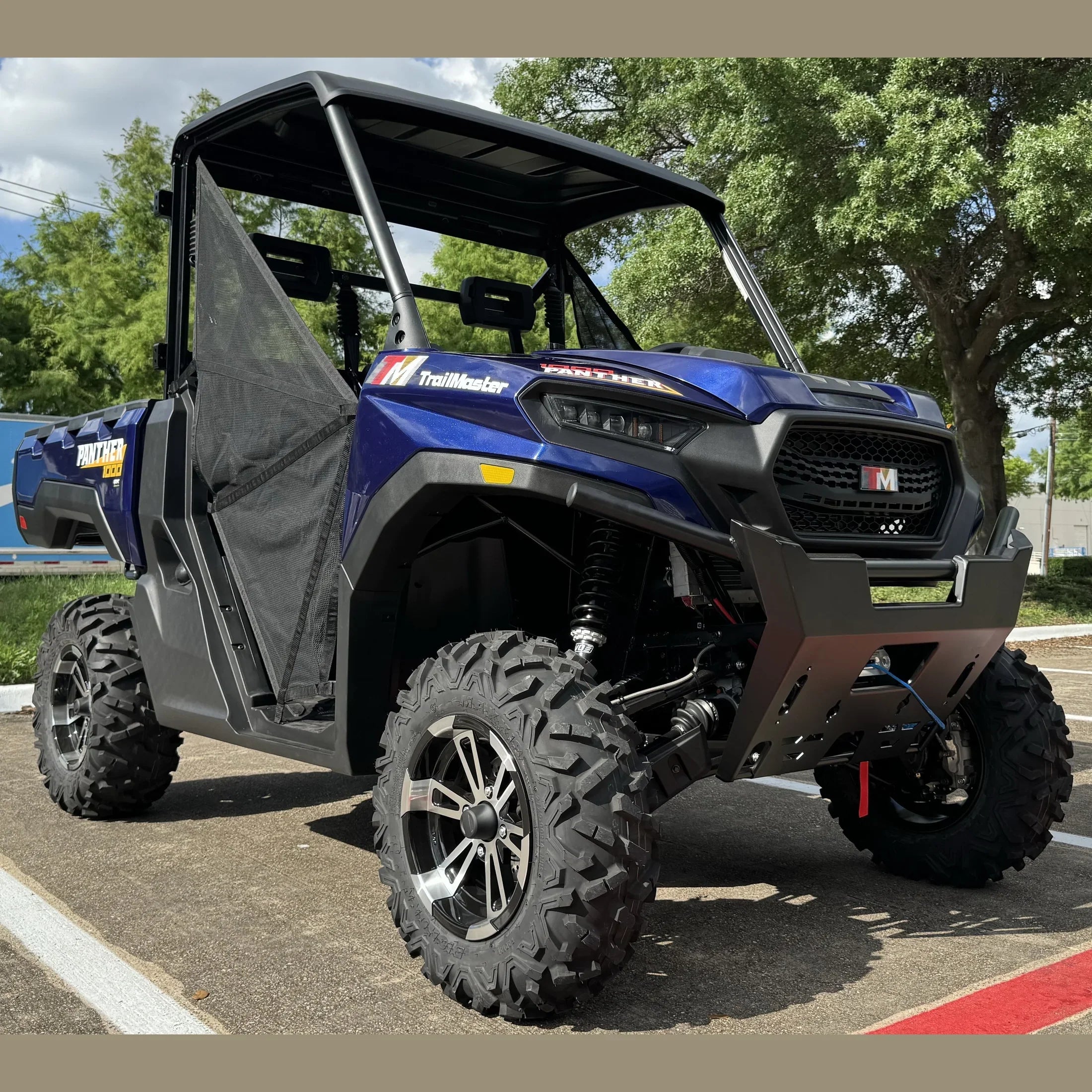 Blue TrailMaster Panther 1000 UTV with rugged tires and roll cage parked outdoors