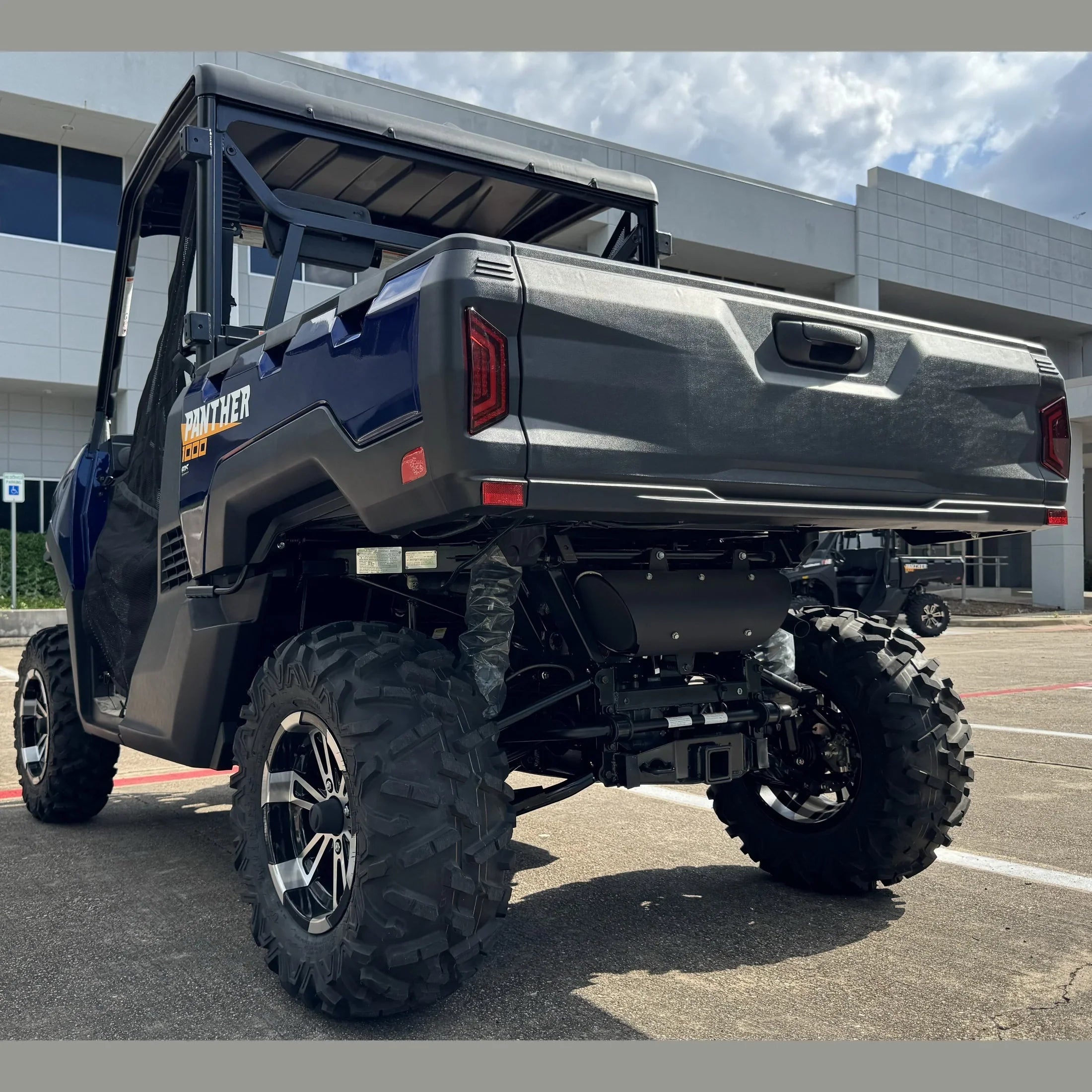 Blue Panther 1000 UTV with large off-road tires parked outdoors, rear view showing cargo bed and rugged design