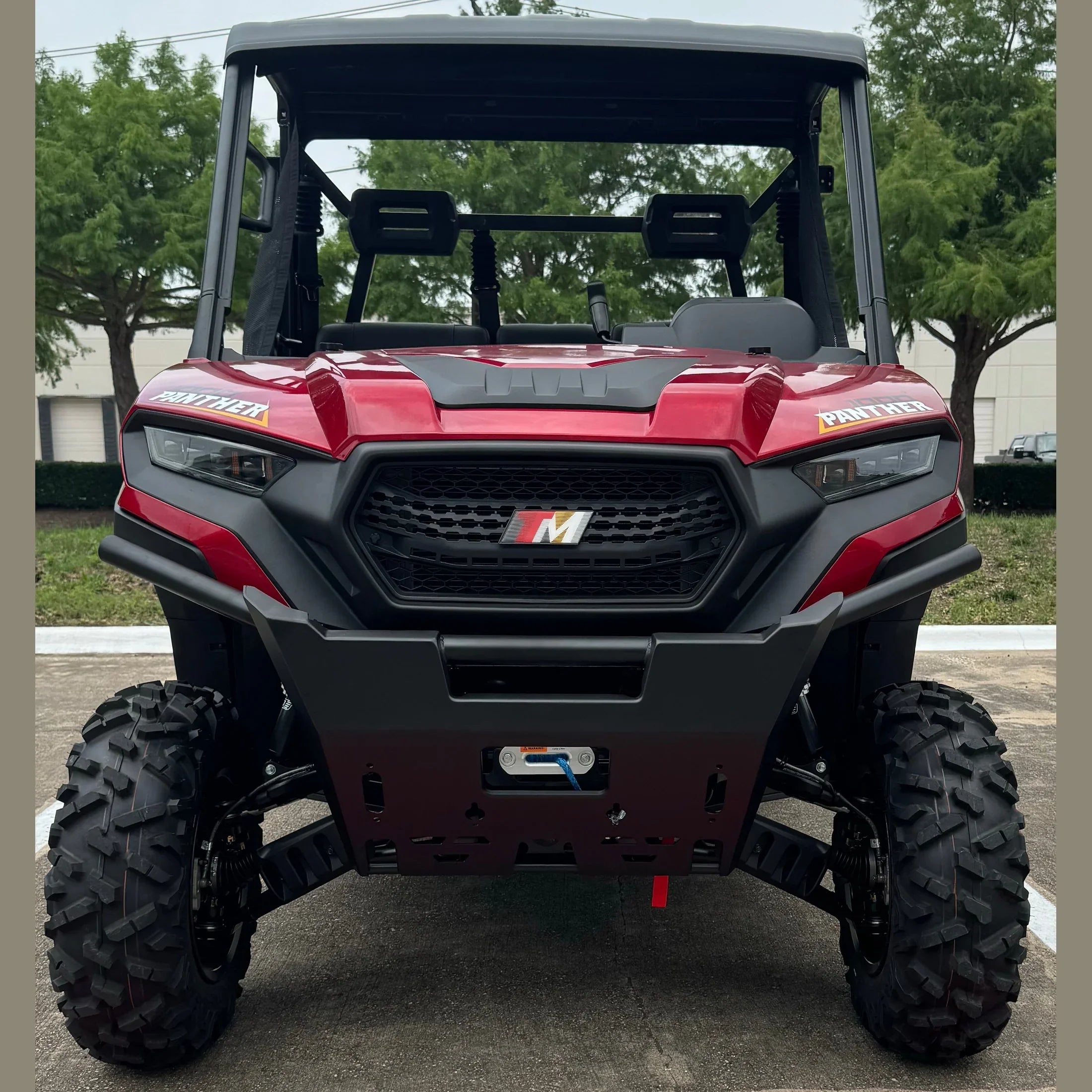 Red and black Panther UTV with rugged tires, front grille, and winch, parked outdoors