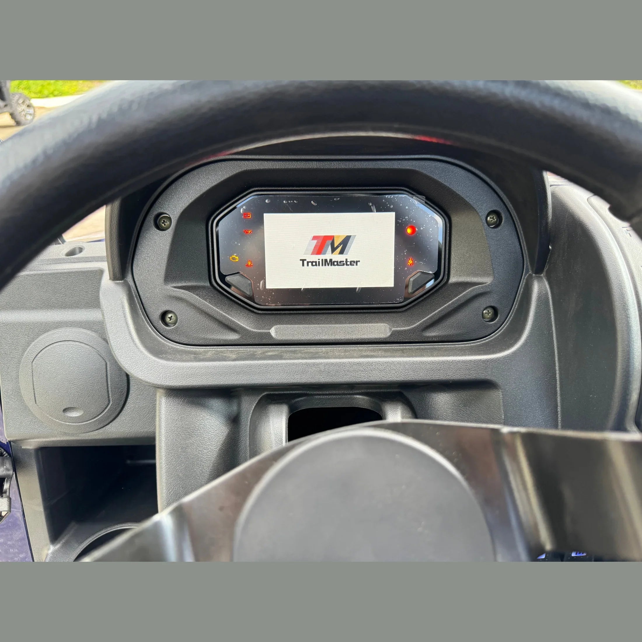 TrailMaster digital dashboard display on UTV with illuminated warning lights and steering wheel view