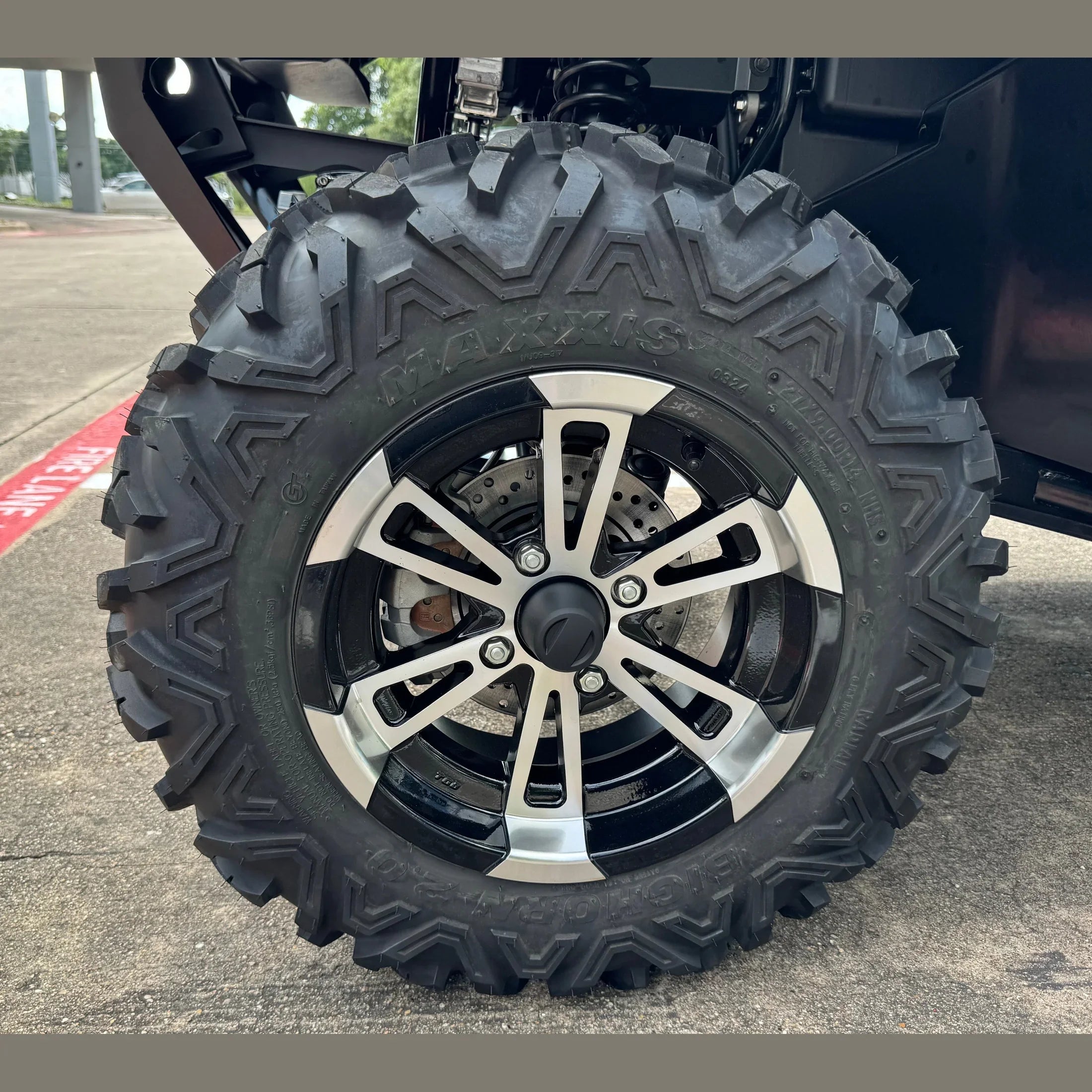 Maxxis off-road tire on UTV wheel with aggressive tread and silver-black rim