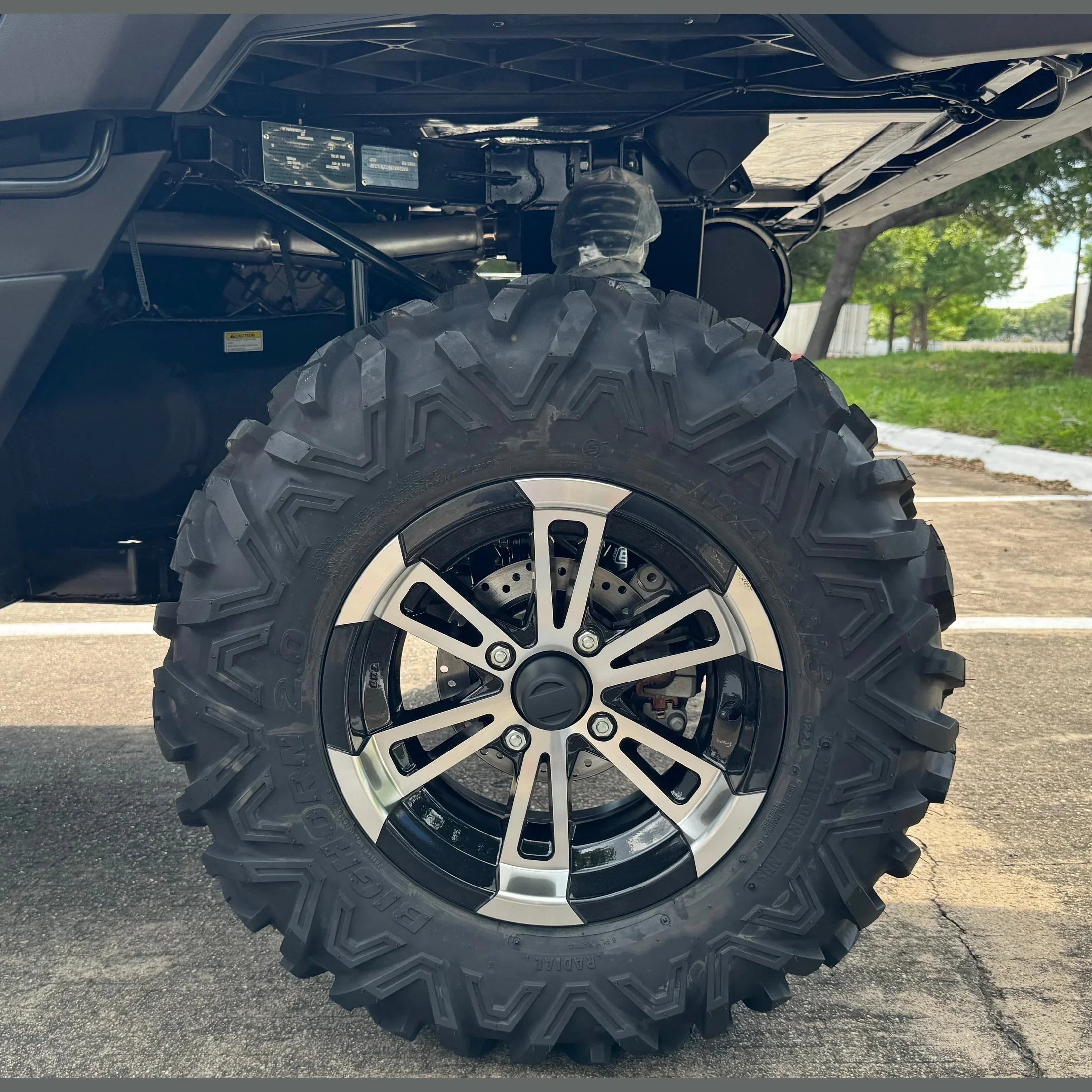 Big Horn 2.0 UTV tire with silver alloy rim and disc brake, shown under vehicle on pavement