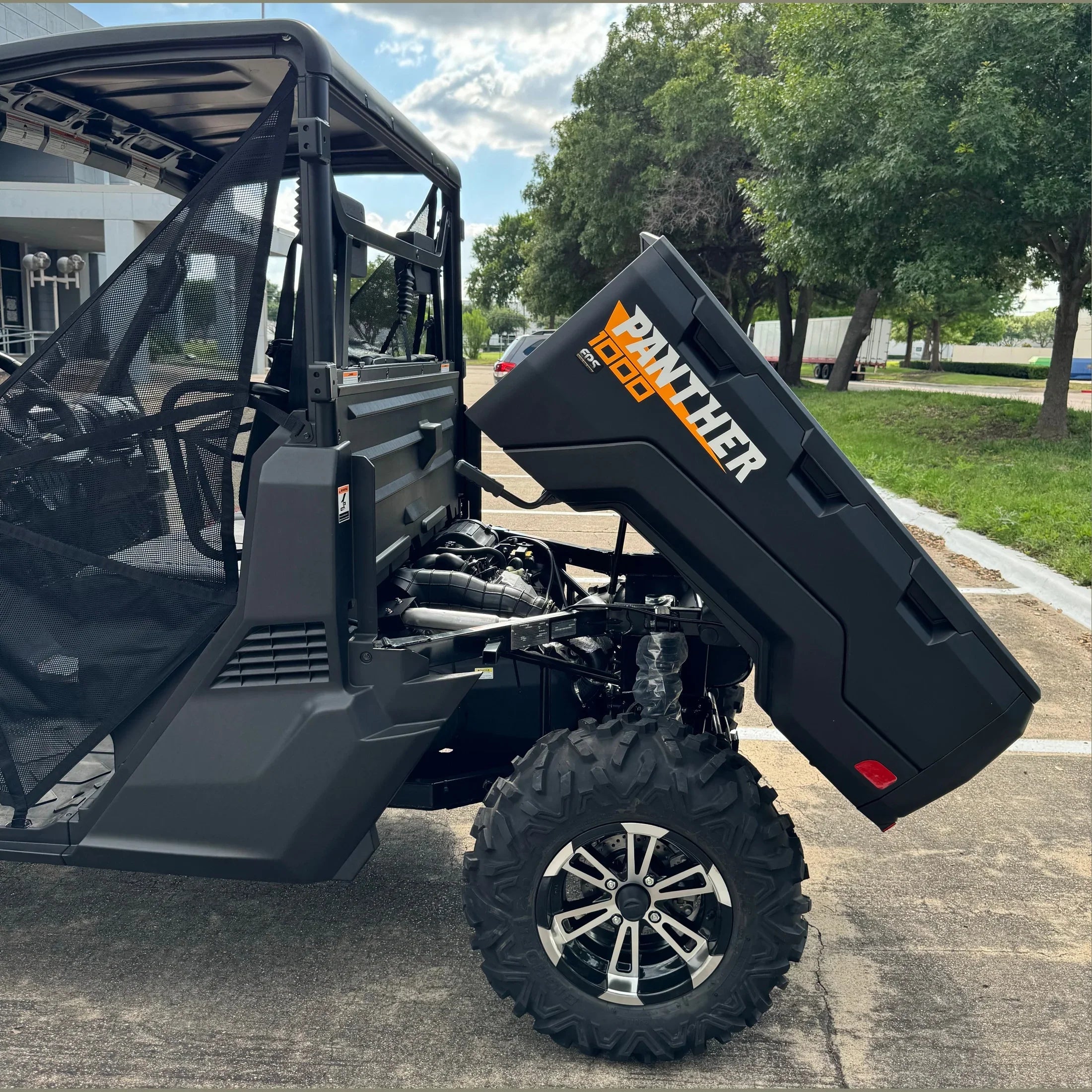 Black Panther 1000 UTV with open hood, showing engine and rugged tires in parking lot