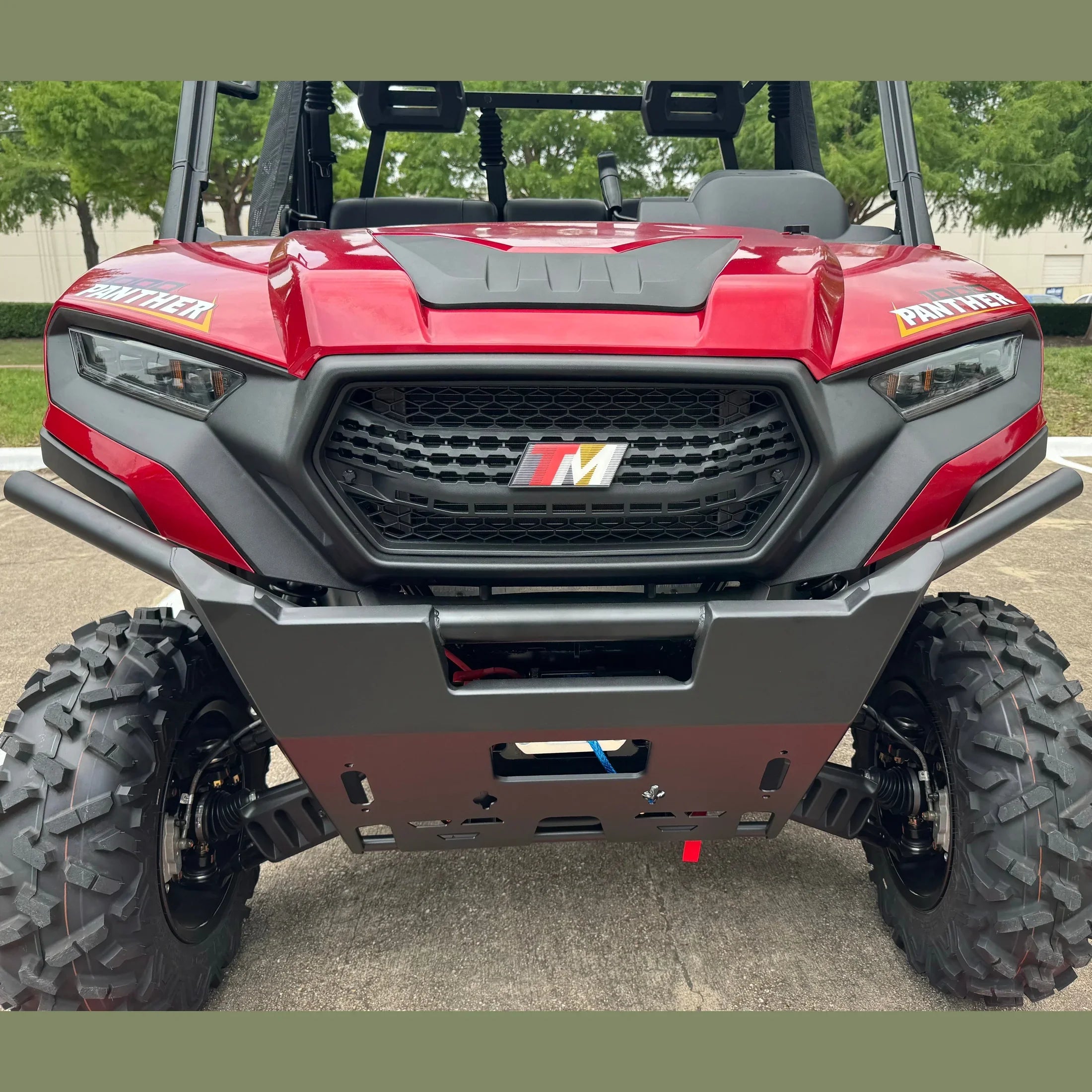 Red TM Panther 1000 UTV with aggressive front grille, off-road tires, and protective bumper for rugged terrain