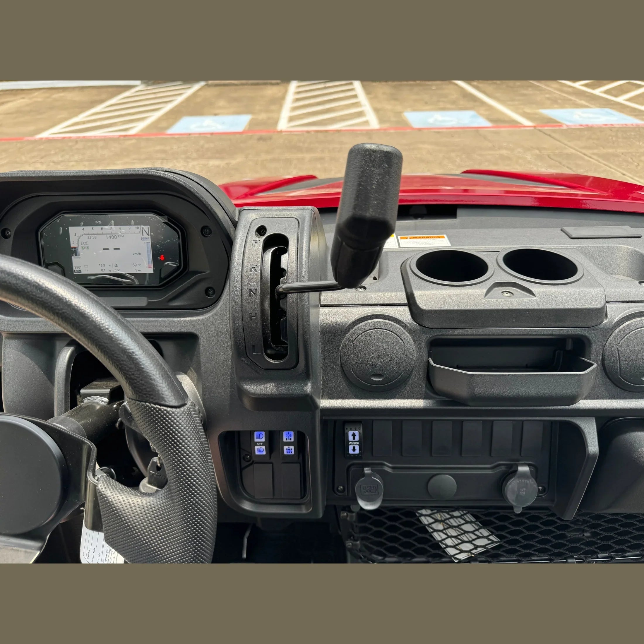 Red UTV interior with digital dashboard, gear shifter, cup holders, and USB ports for off-road adventures.