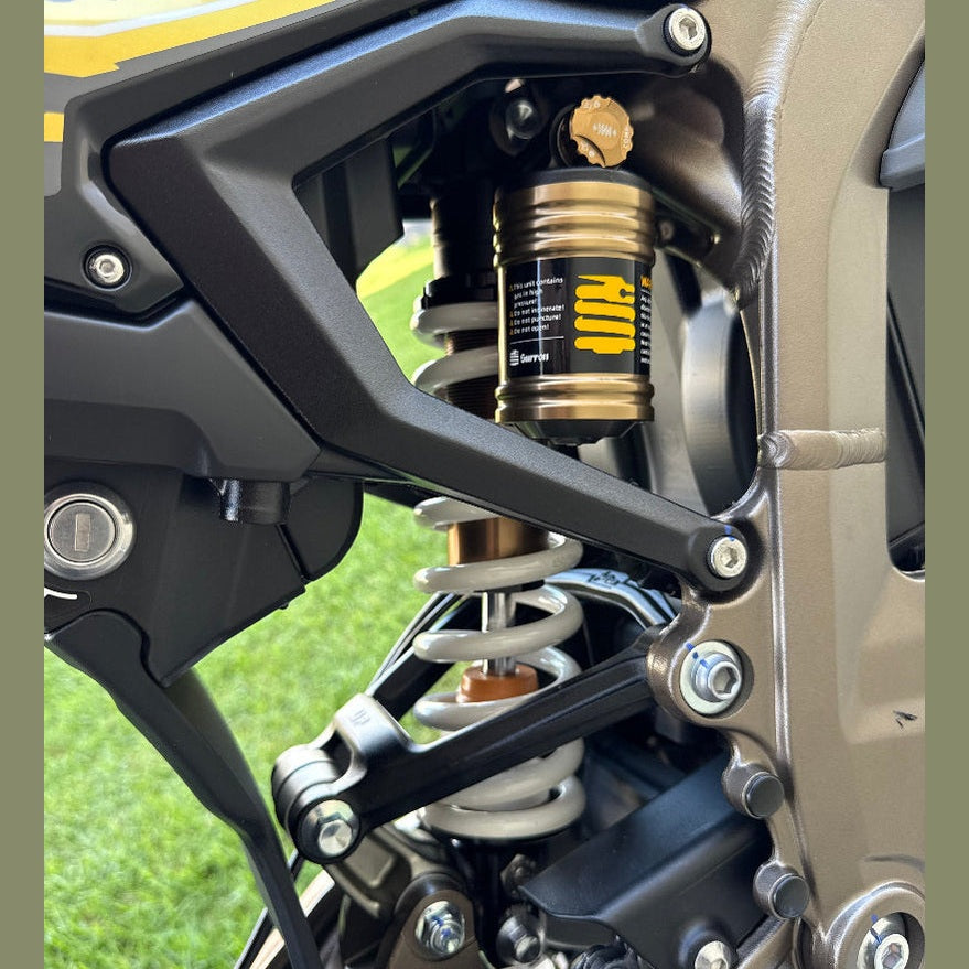 Surron Ultra Bee rear suspension close-up featuring gold shock absorber and white coil spring