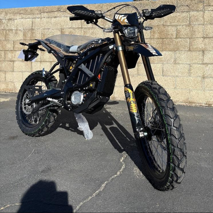 Side view of black Surron Ultra Bee R e-bike on asphalt showing chain drive