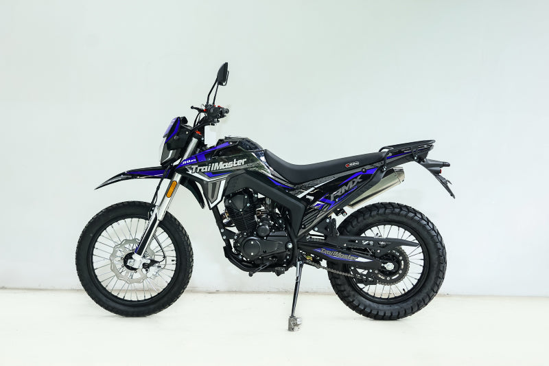 Black and blue TrailMaster RMX250 dual sport motorcycle side view studio shot