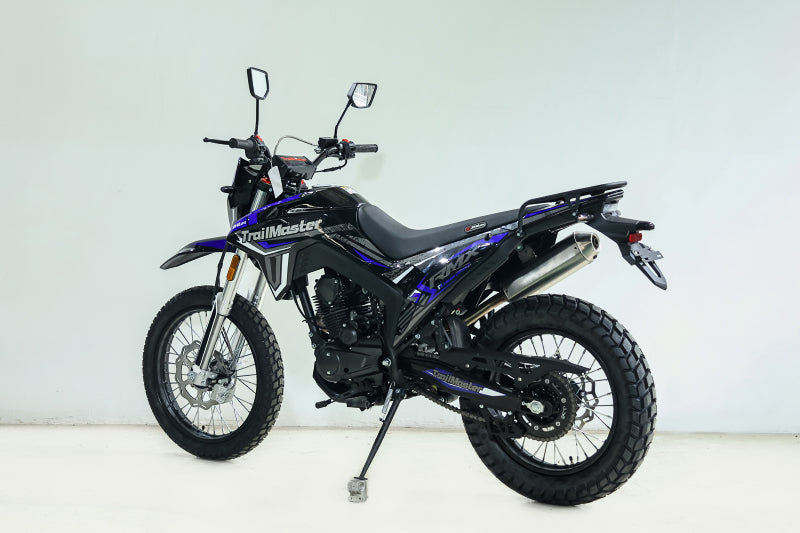 Blue TrailMaster RMX250 enduro bike studio shot showing exposed engine and disc brakes