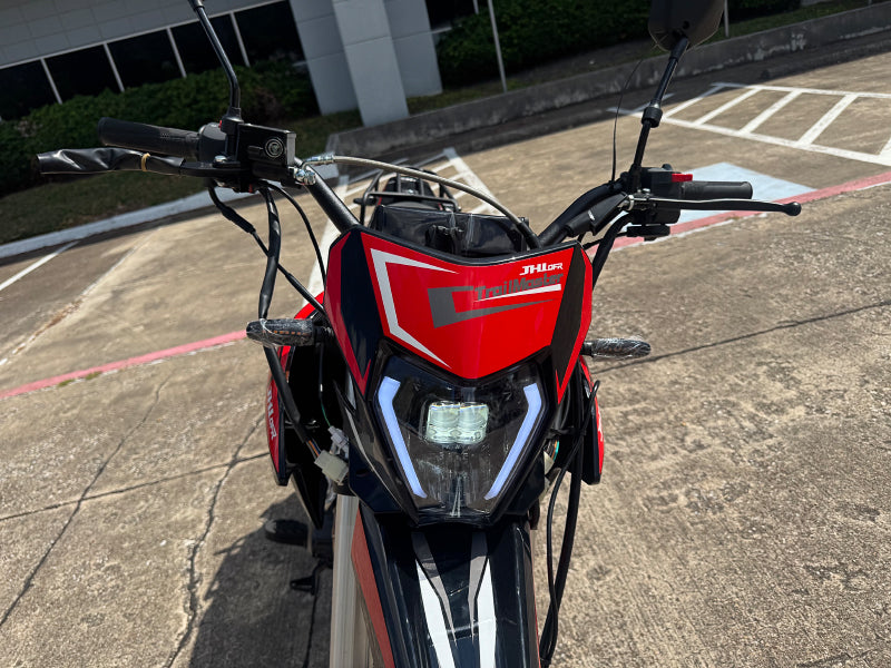 Close-up of TrailMaster RMX250 LED headlight assembly with geometric logo