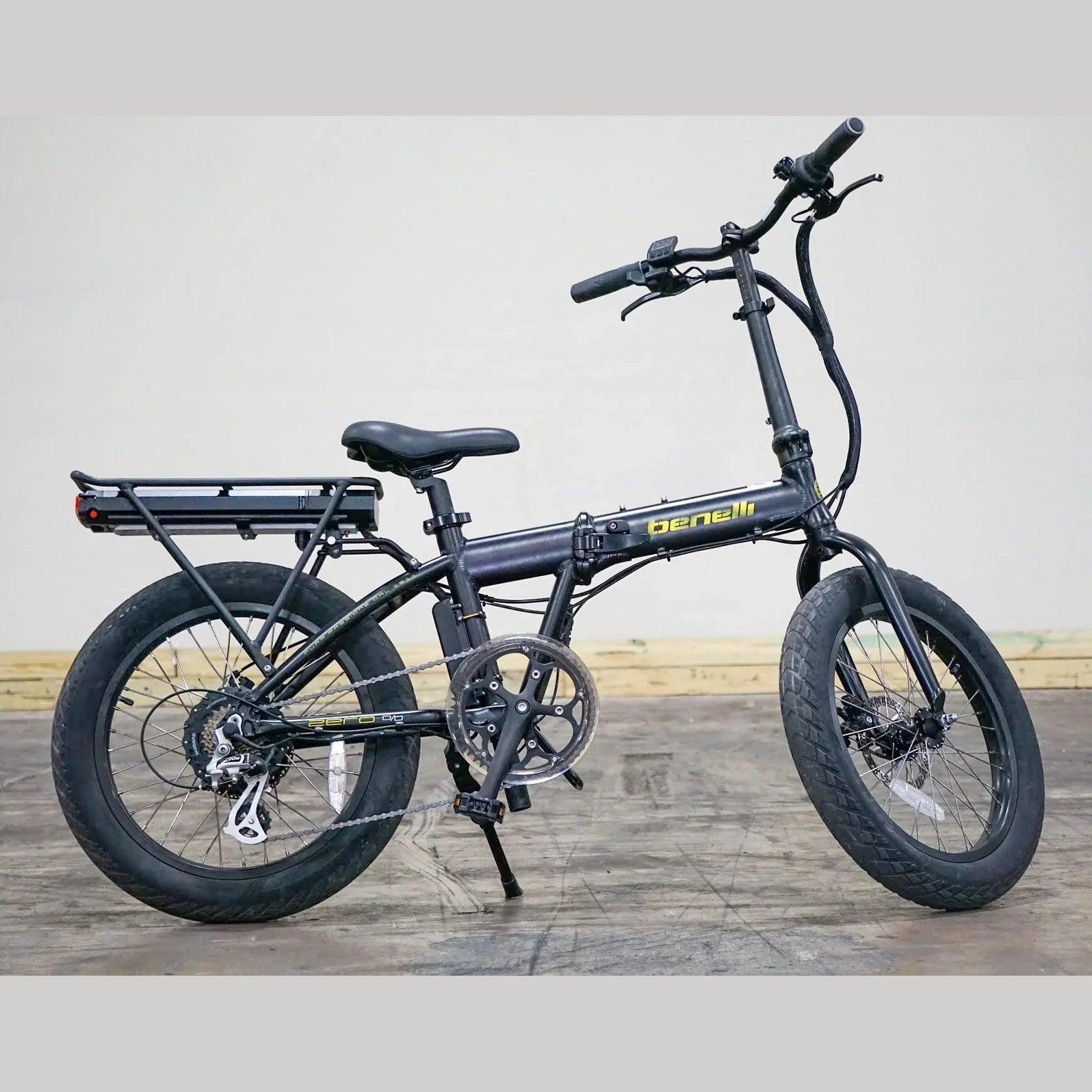 Black Benelli E-Fold 500 on wooden floor showing exposed drivetrain and folding joint