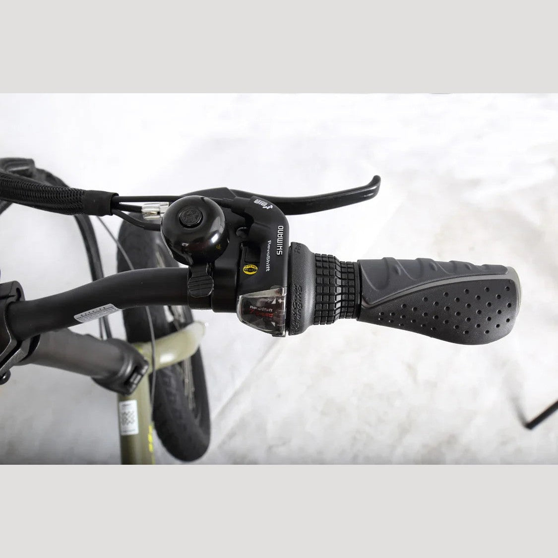 Olive green Benelli handlebar close-up with Shimano shifter, brake lever, and bell