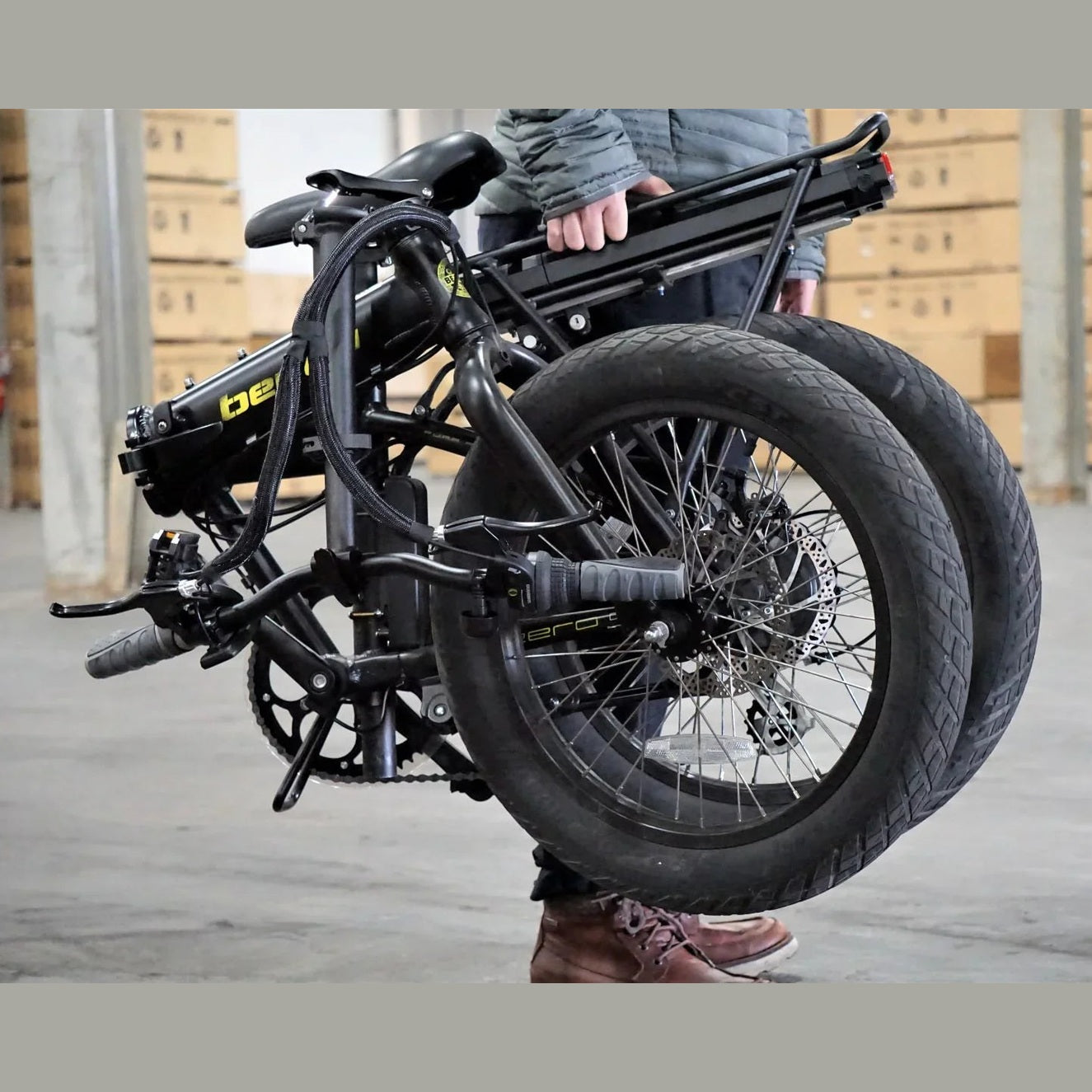 Person holding fully folded black Benelli e-bike demonstrating portability
