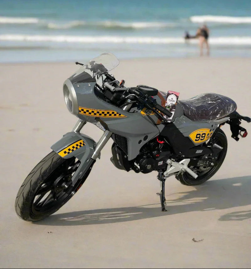new american lifan kp master motorcycle with decals parked on a sandy beach near the ocean.