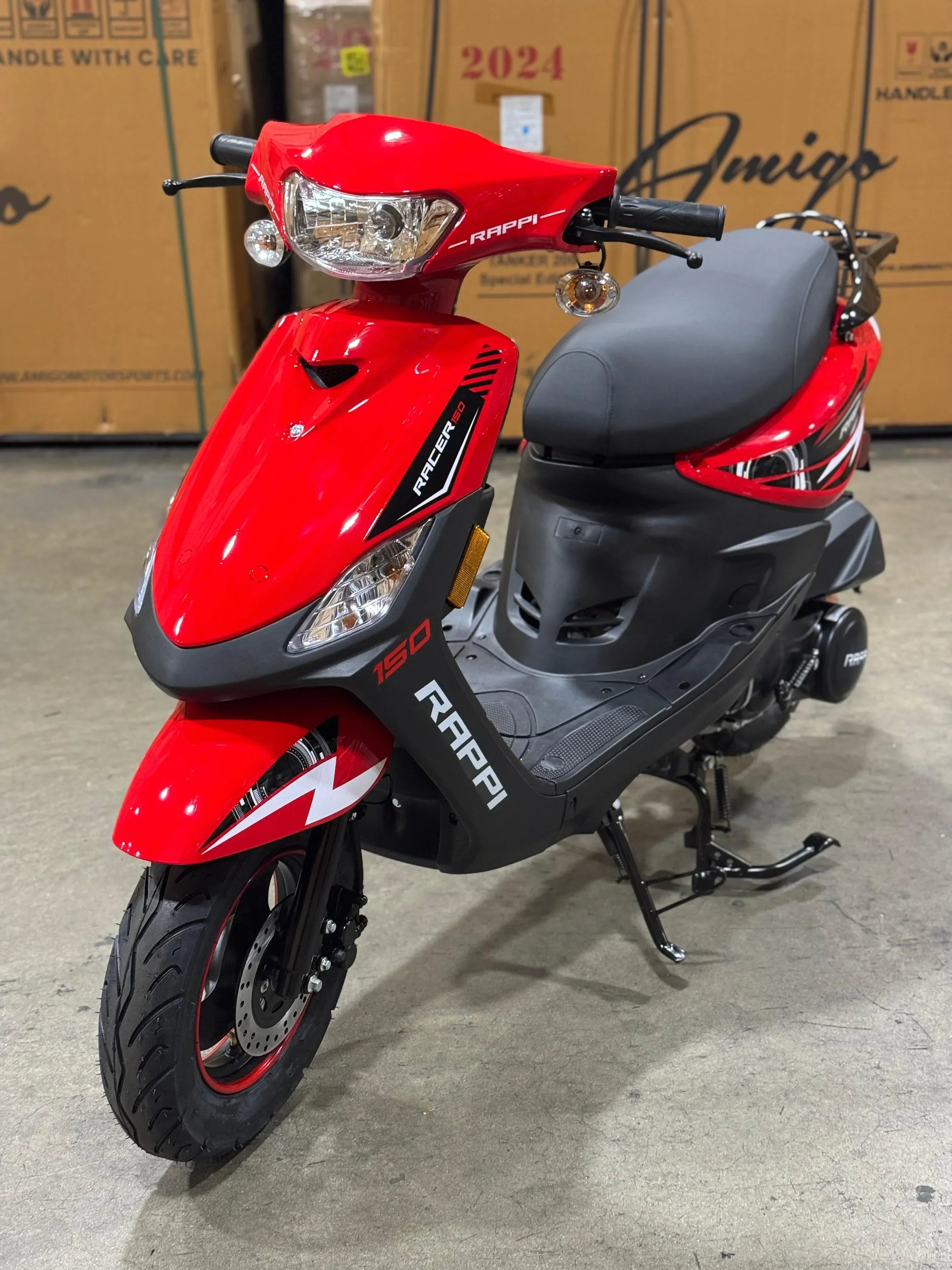 Red RAPPI Racer 150 scooter with black accents, front disc brake, and storage rack, displayed in warehouse.