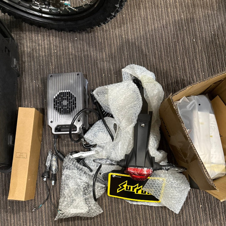 Surron Ultra Bee accessories including charger, rear fender with taillight, and license plate holder