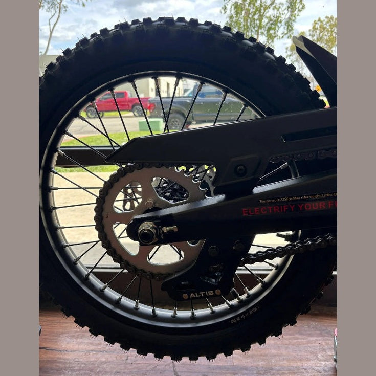 rear wheel of black Atlis Sigma e-bike showing chain drive and knobby tire tread