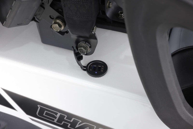 Close-up of dual USB charging ports on white Turbo Powersports vehicle near bolts and black seatbelt