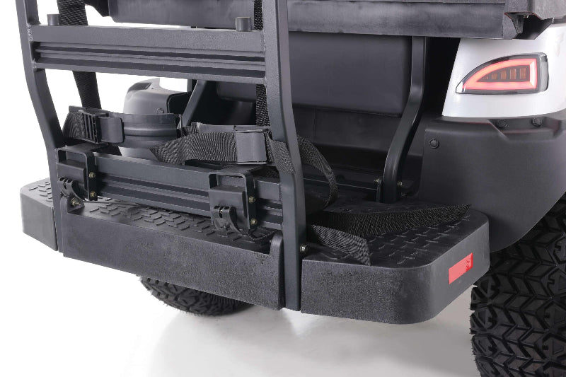 Close-up of rear step and seat straps on a black utility vehicle with textured tire tread